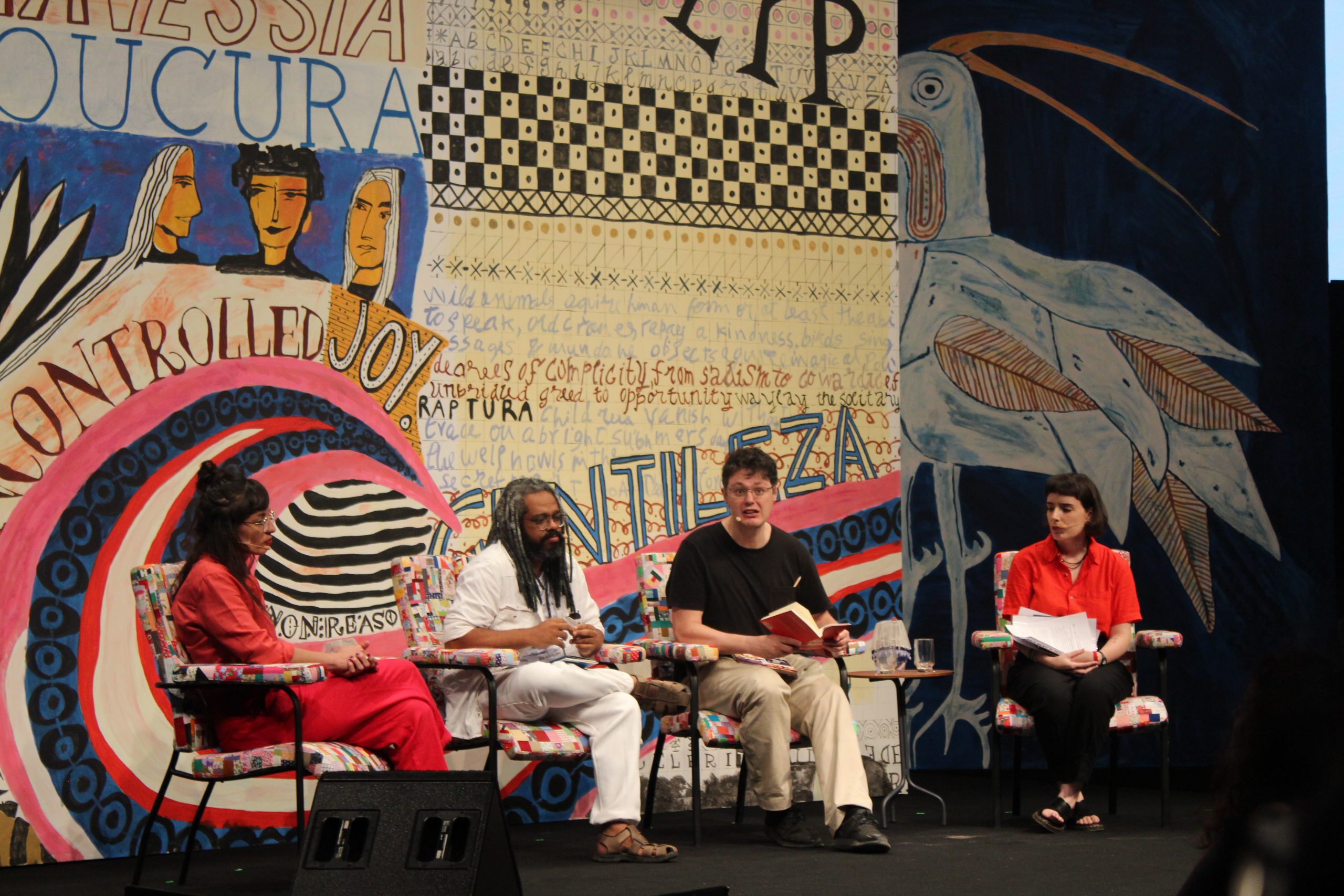 Mesa com o autor surdo, destaque da Flip, Ilya Kaminsky . Eles está sentado no palco com 3 autores.